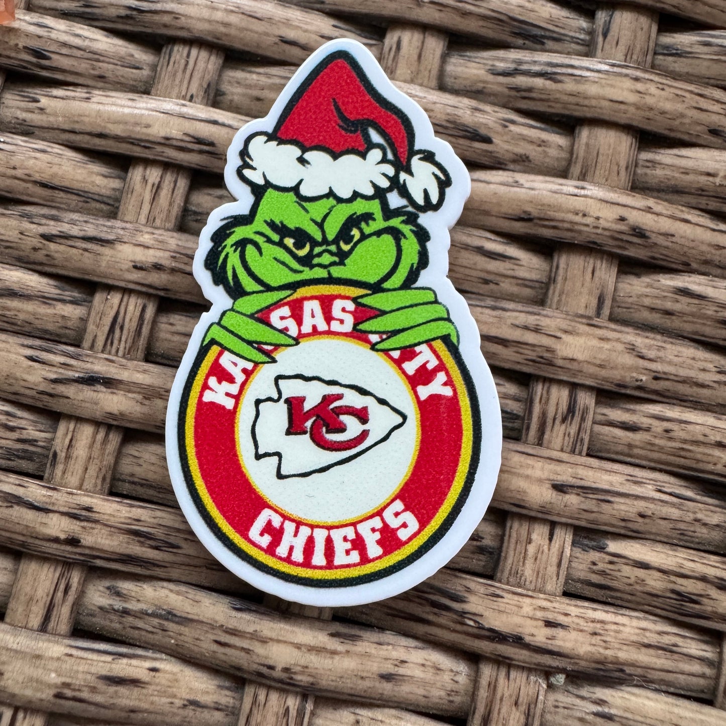 Sticker with a green character holding a red and white object on a woven surface