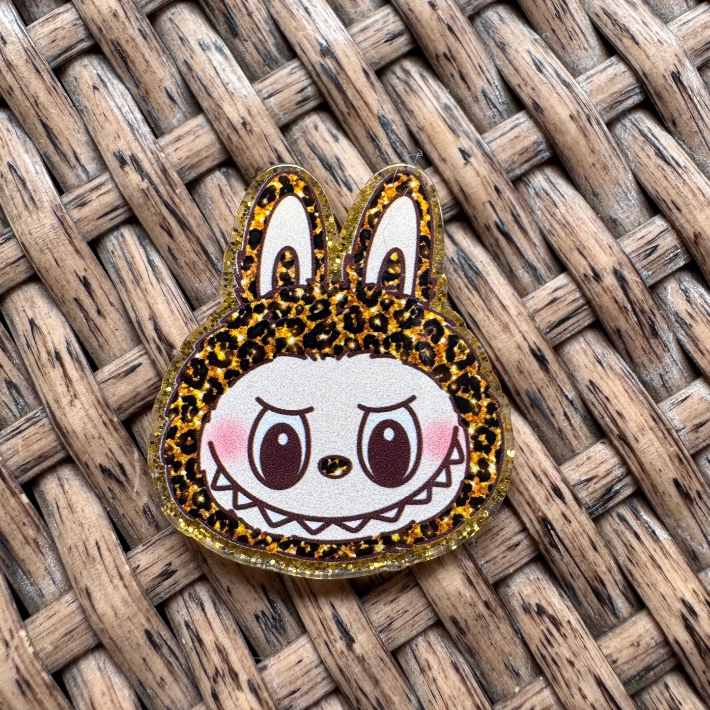 Cartoon character with leopard print ears on a woven surface, Acrylic Flatback