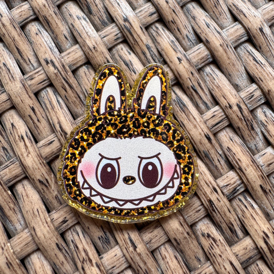 Cartoon character with leopard print ears on a woven surface, Acrylic Flatback